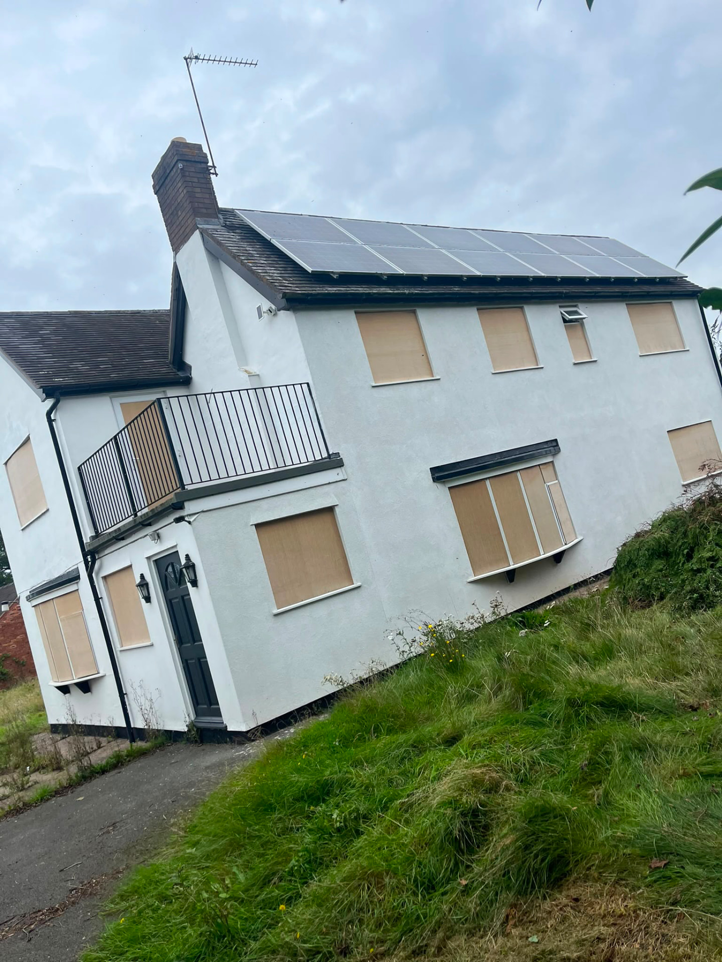 Osbaston Cottage before work began, windows boarded and render weathered