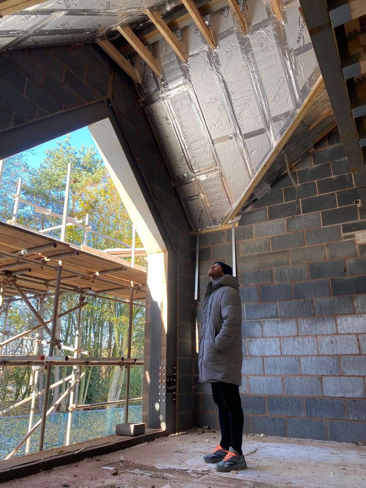 Builder inspecting a vaulted, fully insulated roof structure inside a home under construction