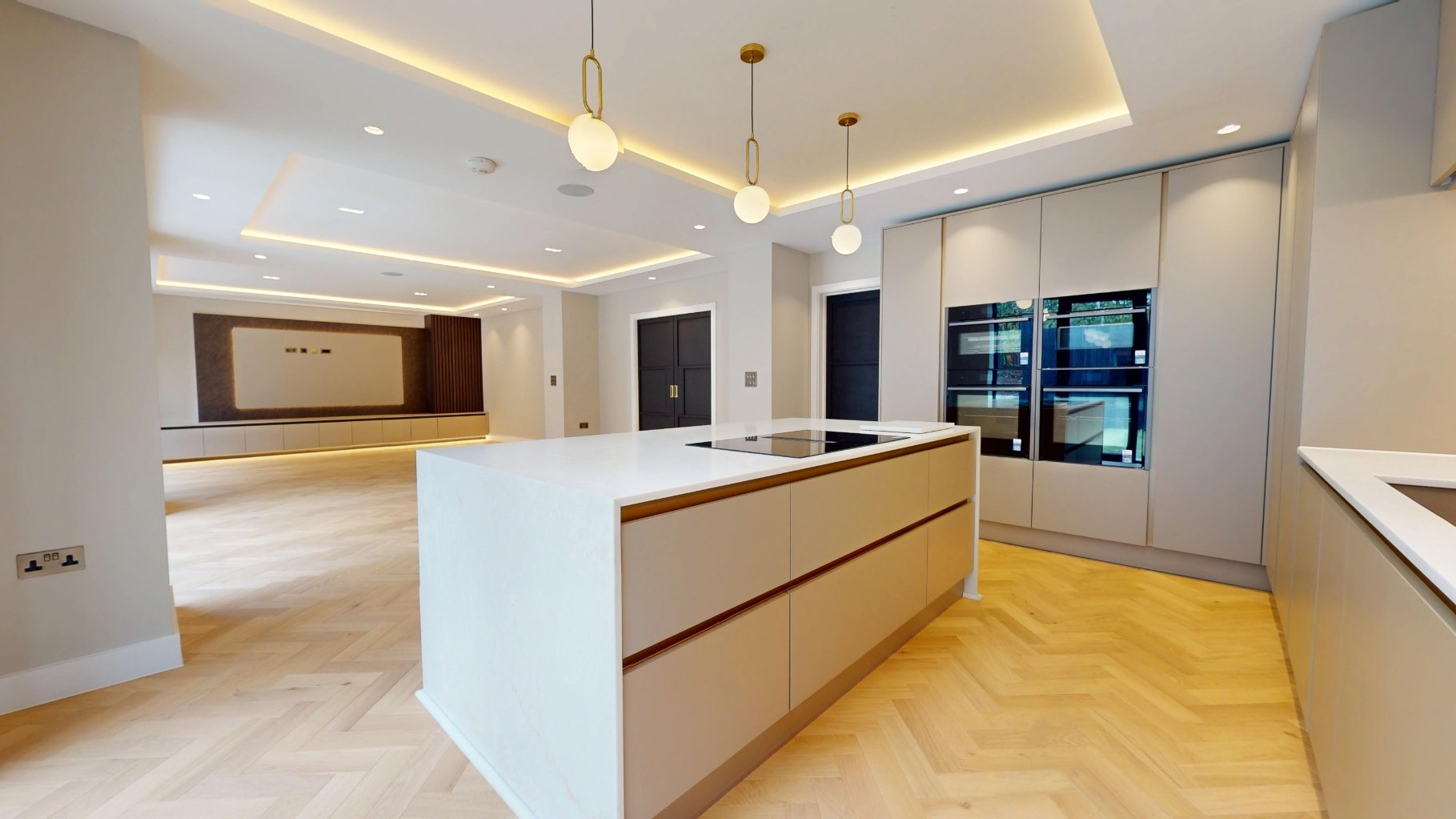 Open-plan kitchen with handleless cabinetry, stone island and herringbone oak flooring