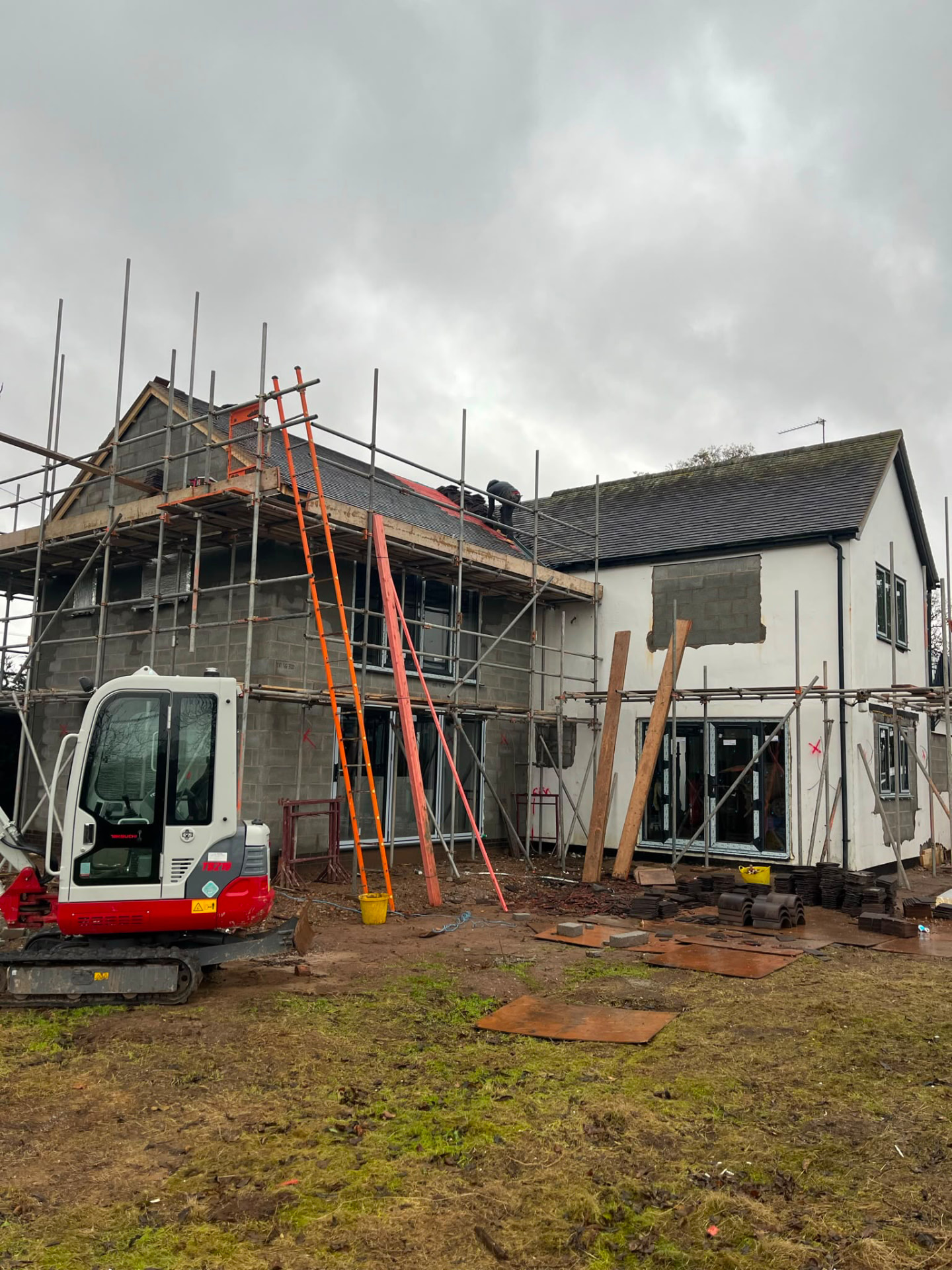 Extension shell under scaffold with roof tiling underway