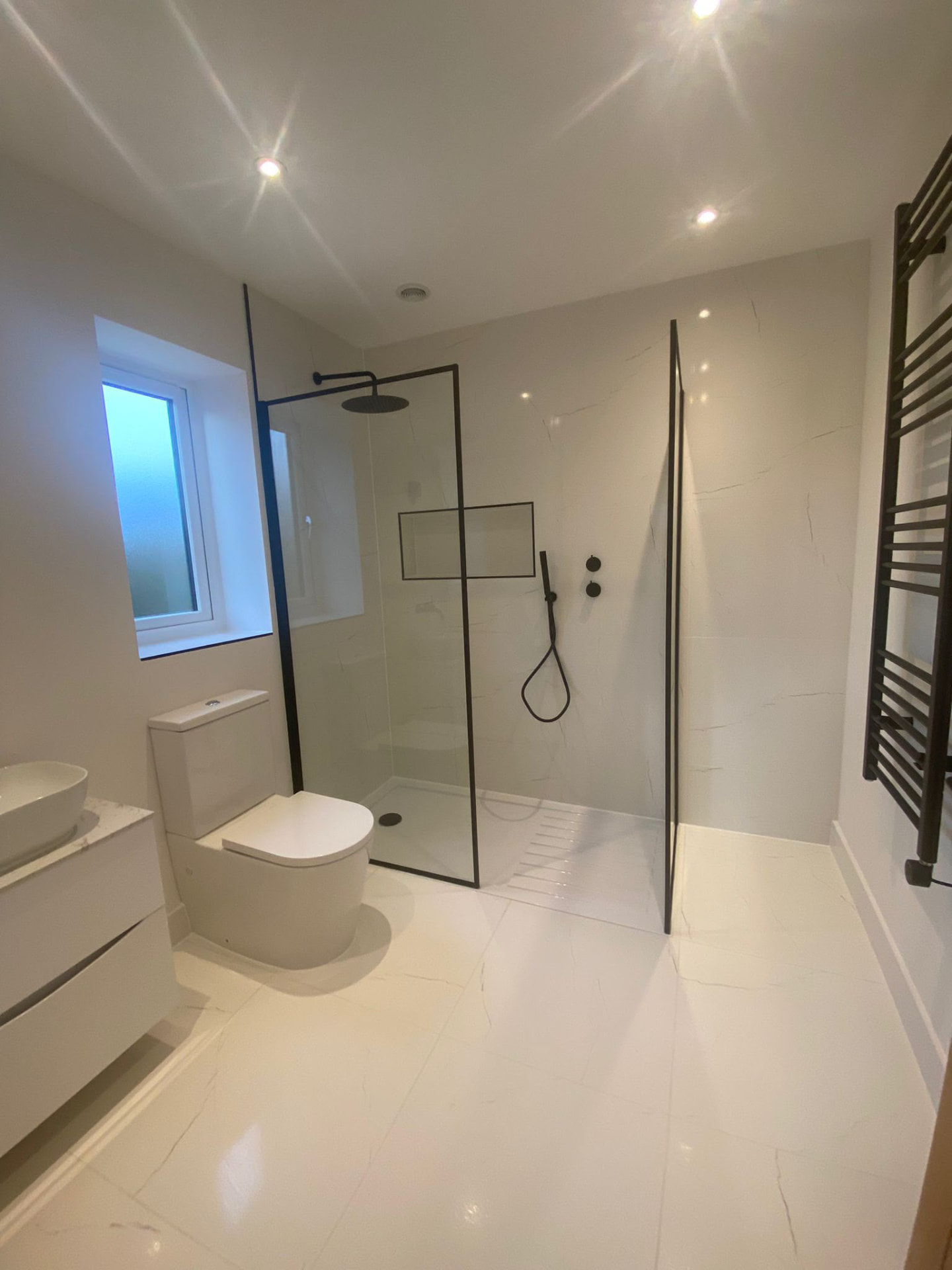 Marble tiled bathroom with walk in shower and black brassware