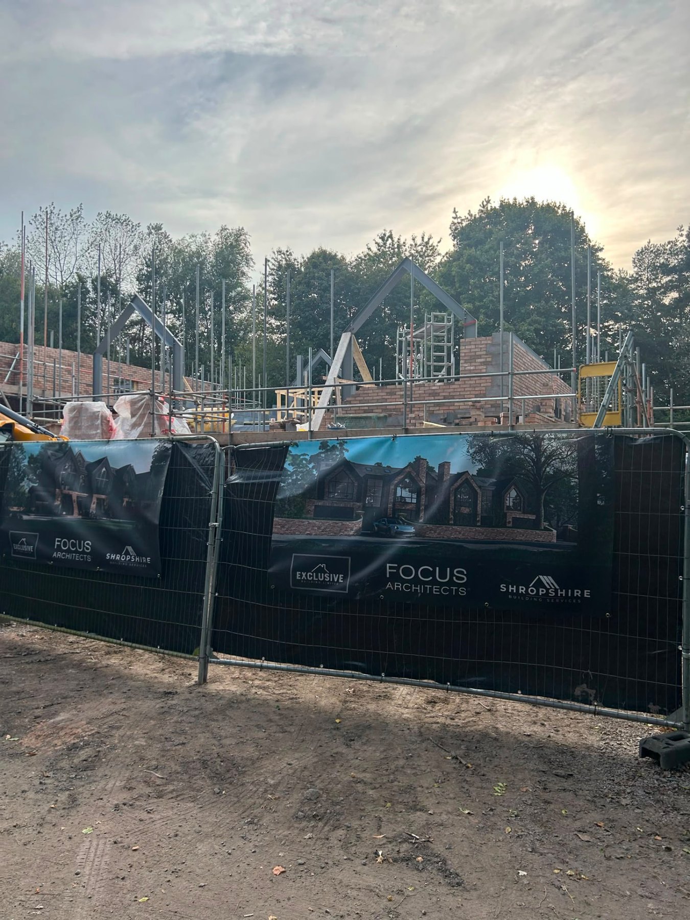 Site hoarding carrying the Exclusive Building, Focus Architects and Shropshire Building Services banners in front of a home under construction