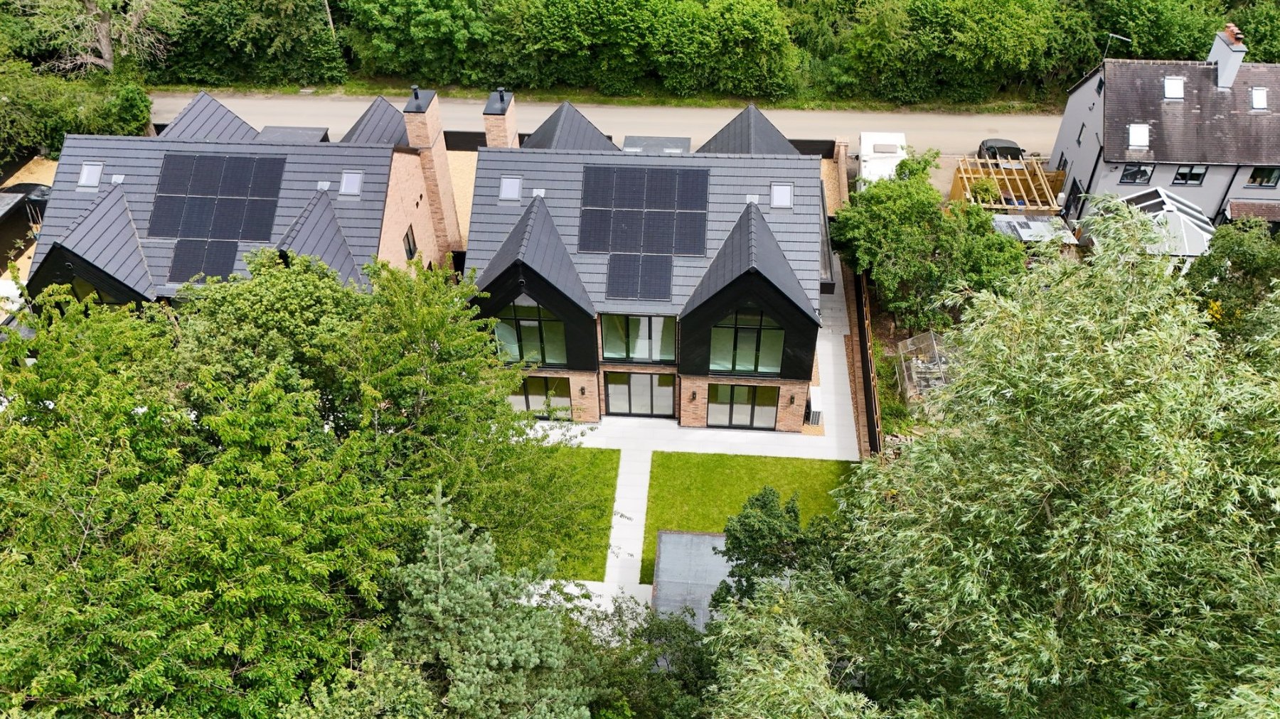 Drone view of the finished home and its solar roof surrounded by mature trees