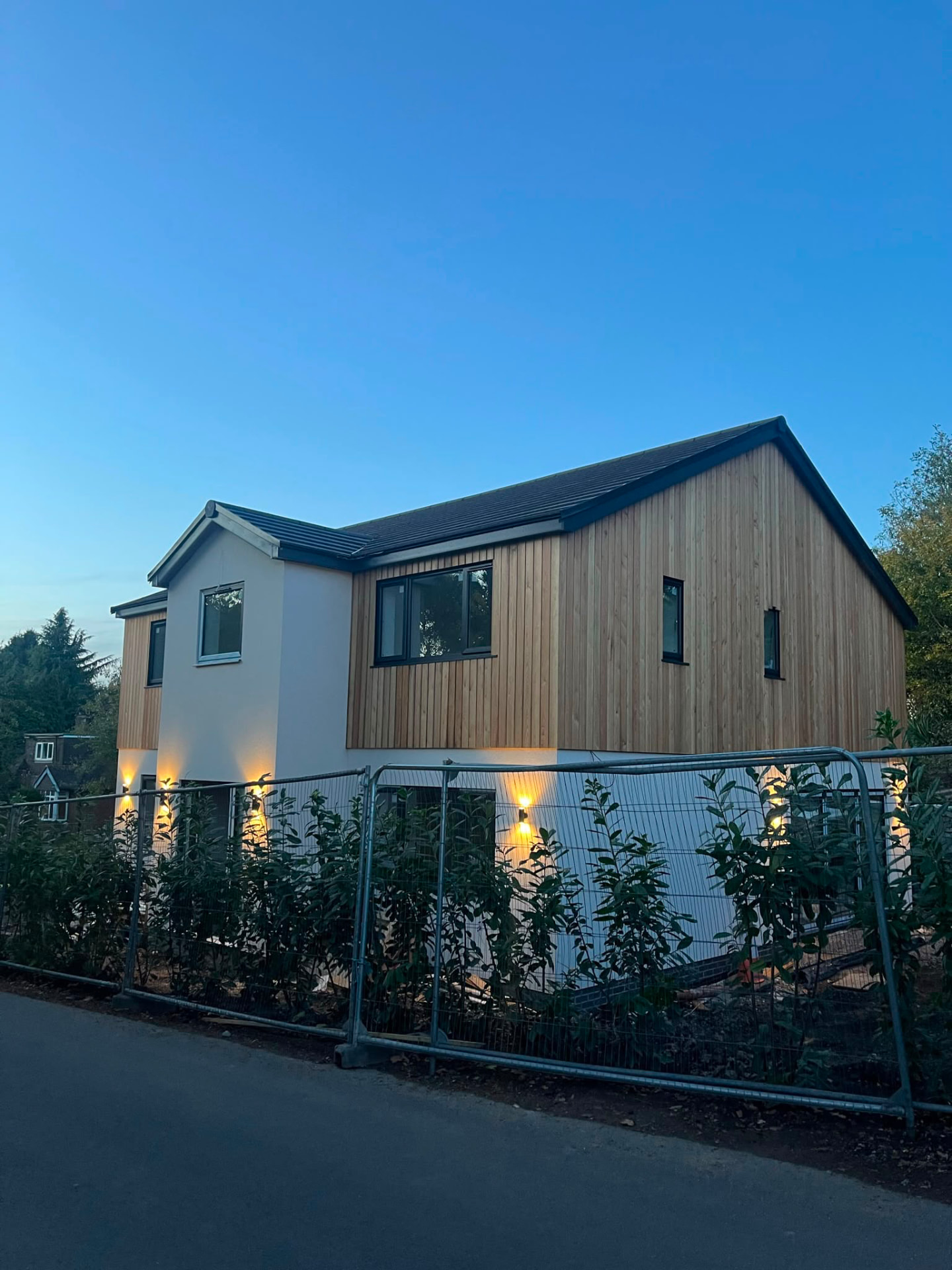 Ashwood House at dusk with exterior lighting washing the render and cedar cladding